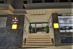 A hotel entrance with a star logo, marble steps, and potted plants.