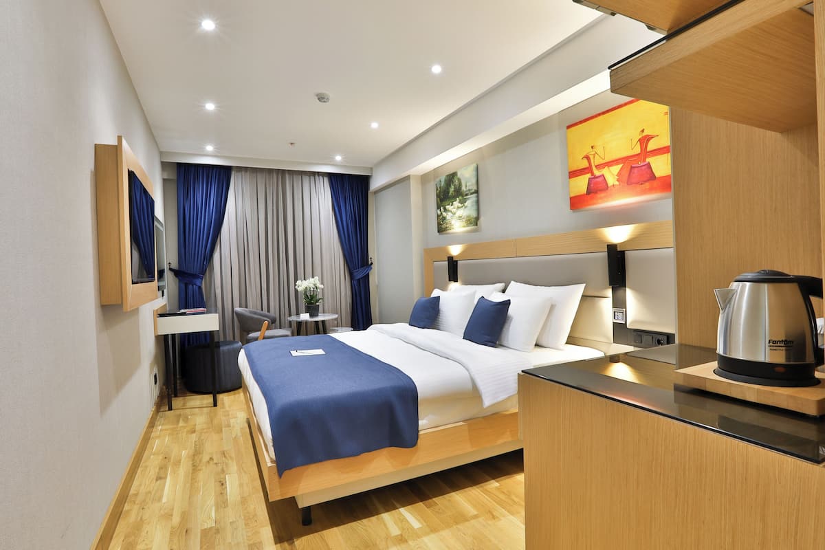 Una habitación de hotel moderna con cama, mesita de noche y hervidor en la encimera.