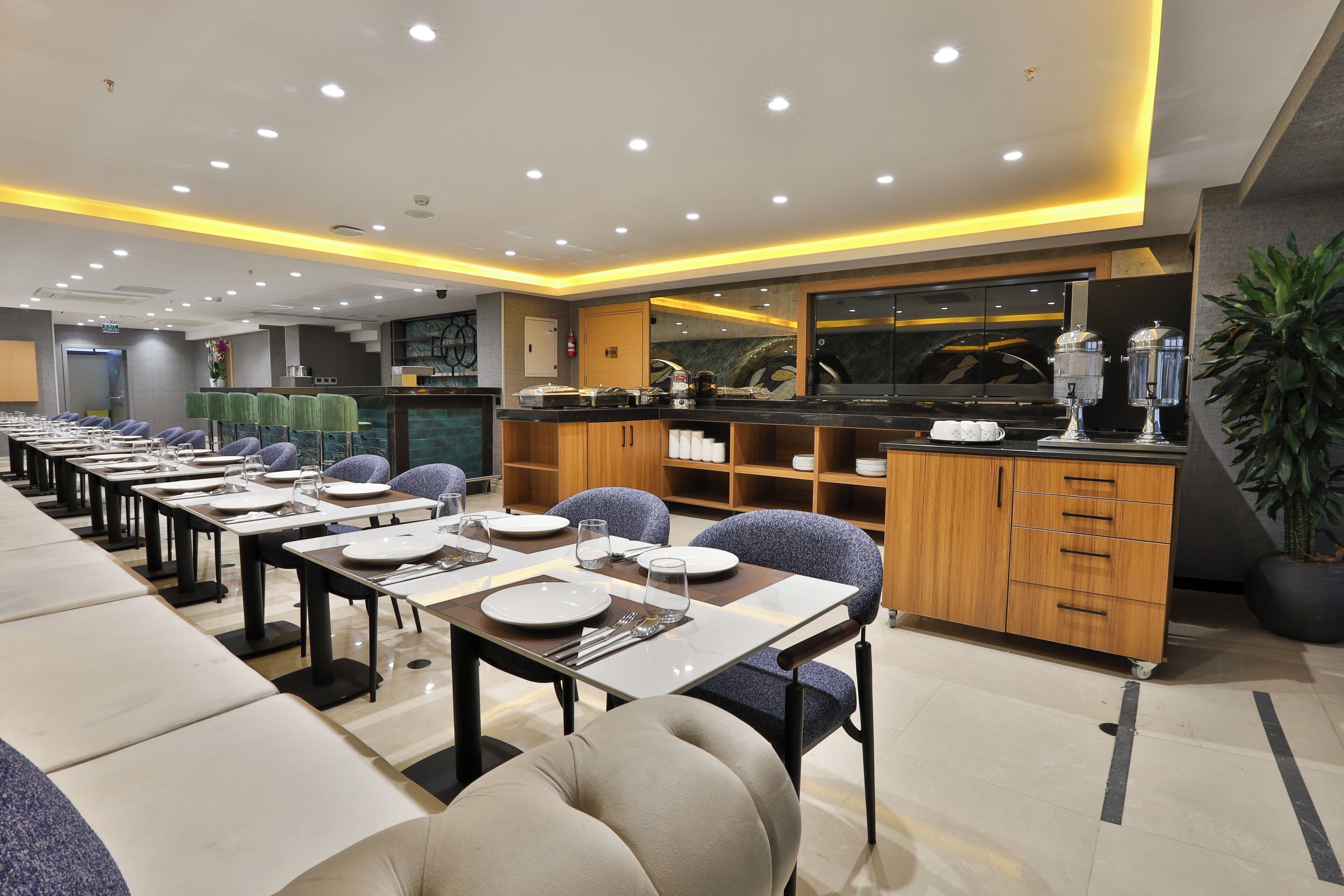 Un comedor moderno con mesas largas, sillas y una estación de buffet.