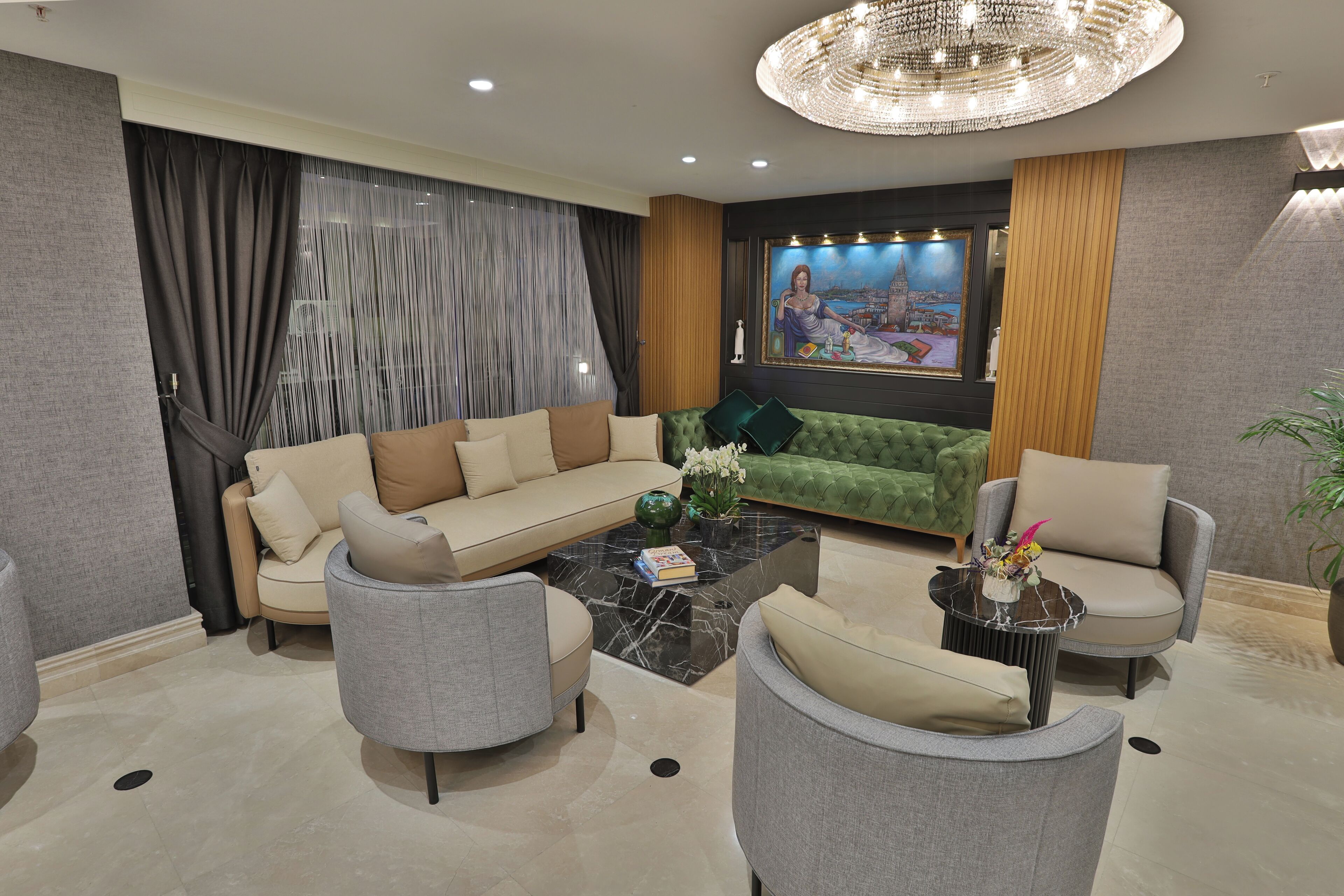 A modern living room with a green sofa, grey armchairs, and a black coffee table.