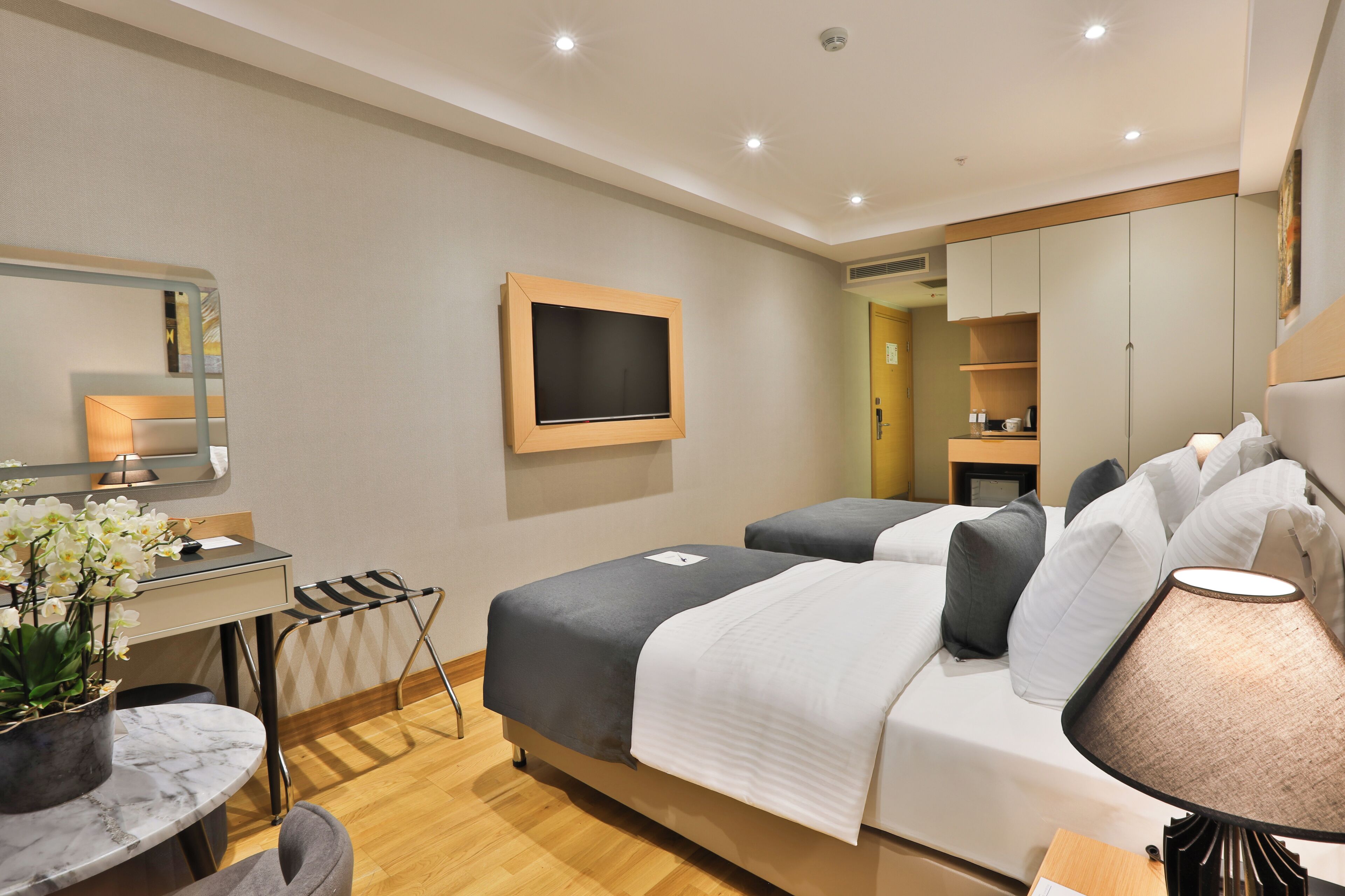 A hotel room with a bed, bedside table, lamp, and a desk with a chair.
