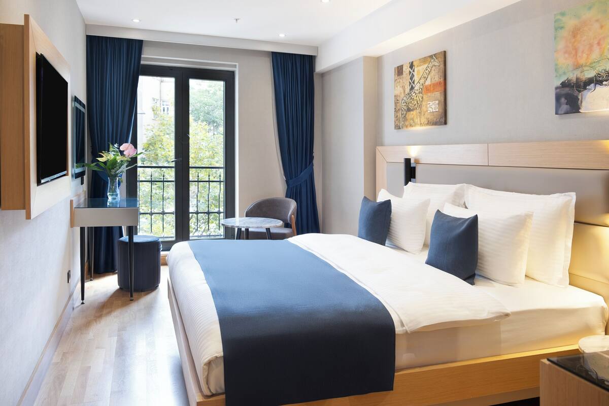 Un hotel moderno con una cama grande, un escritorio, una silla y vistas al exterior.