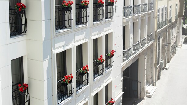 Un immeuble à plusieurs étages doté de balcons, chacun étant agrémenté de fleurs rouges.