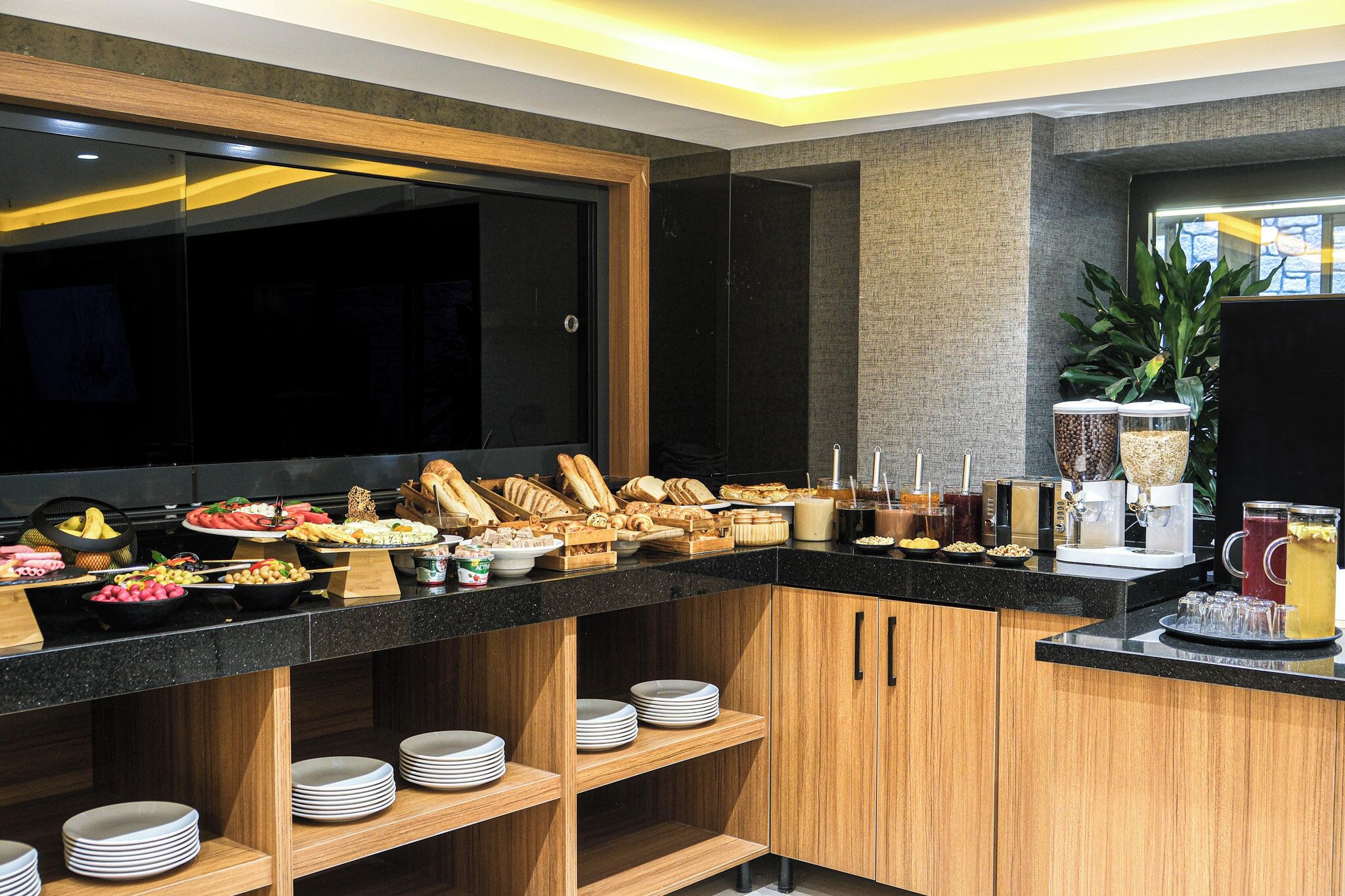 Un buffet proposant une variété de plats et de boissons, des meubles en bois et une grande fenêtre donnant sur un beau paysage.