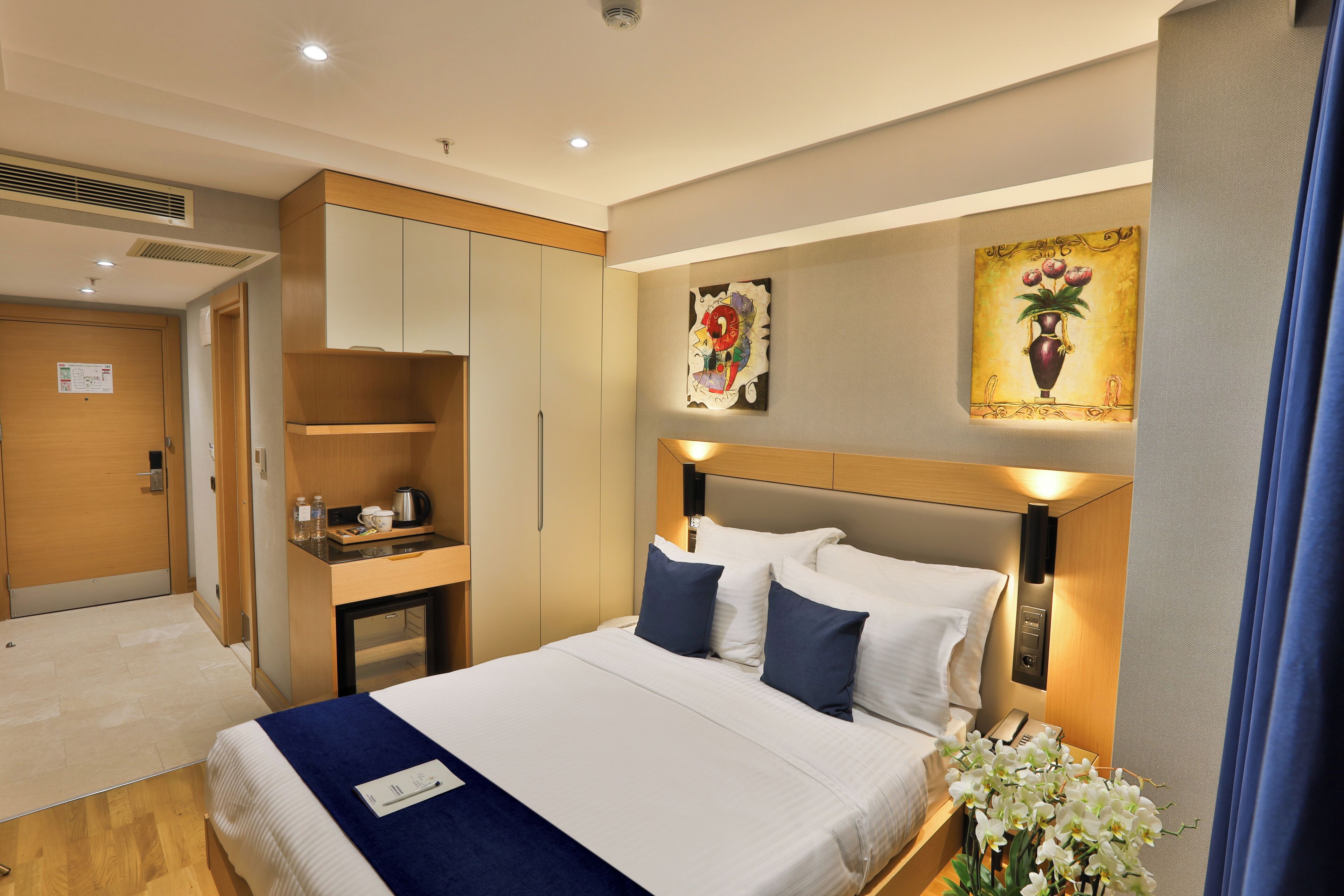 A hotel room with a bed, bedside table, and a desk.