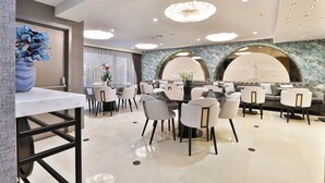 Un espace de restauration moderne avec des tables et des chaises rondes, un sol en marbre et un lustre.