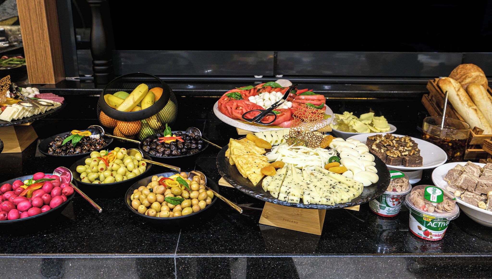 A buffet table with various food items including fruits, cheeses, and bread.