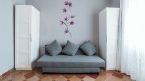 Un sofá gris con tres cojines frente a una pared decorada con motivos florales.