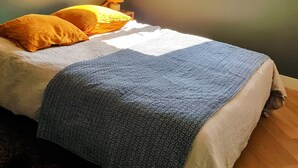 Un lit avec une couverture à motifs, un oreiller jaune et une table de chevet avec une lampe.