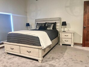 A bedroom with a bed, bedside tables, and a door.