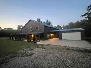 A two-story house with a garage, a covered porch, and a gravel driveway.