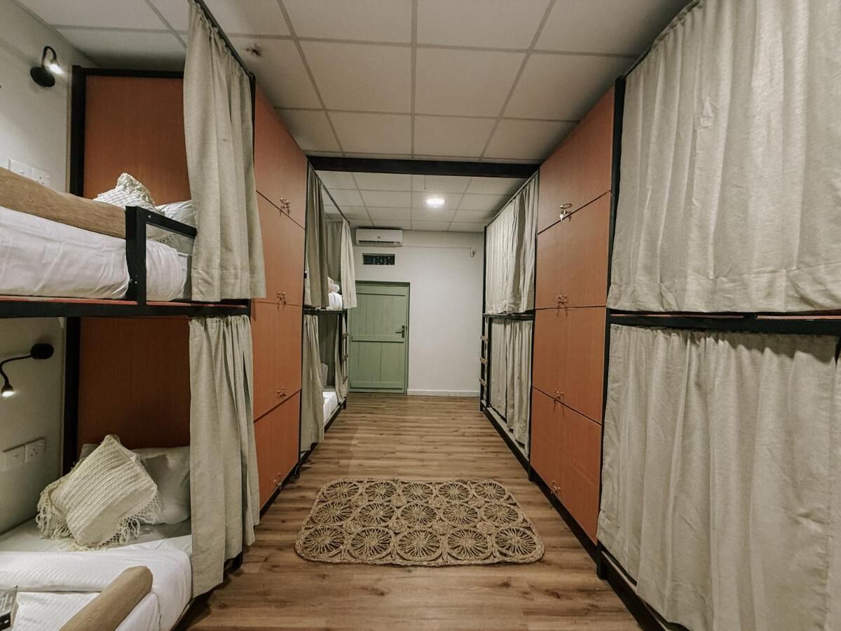 Un corredor estrecho con literas a ambos lados, suelo de madera y una alfombra estampada en el centro.