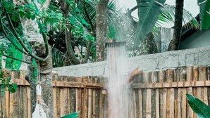 A bamboo water feature with a waterfall, surrounded by greenery and a stone basin. - Kickin' Surf Lodge (Weligama)
