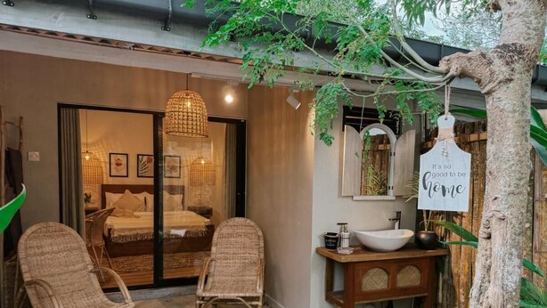 A cozy room with wicker chairs, a large window, and a wooden vanity with a bowl sink. - Kickin' Surf Lodge (Weligama)