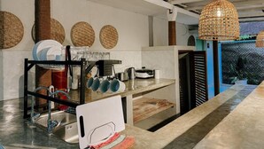 A modern kitchen with a built-in sink, a coffee machine, and a hanging light fixture. - Kickin' Surf Lodge (Weligama)