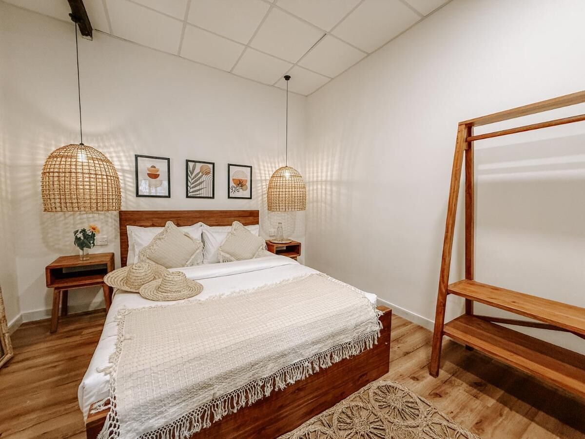 Une chambre à coucher bien rangée, avec un lit en bois, deux tables de chevet et deux lampes suspendues.