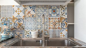 A kitchen with a double sink, colorful tile backsplash, and a white cabinet with a lid. - Isola delle Femmine Apartments by Wonderful Italy (Isola delle Femmine)