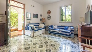 A room with two striped sofas, a television, and a patterned floor. - Isola delle Femmine Apartments by Wonderful Italy (Isola delle Femmine)