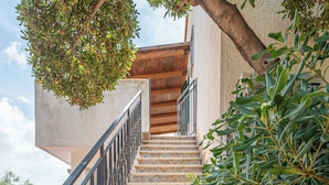 A staircase with patterned tiles leading to a wooden door, surrounded by greenery. - Isola delle Femmine Apartments by Wonderful Italy (Isola delle Femmine)