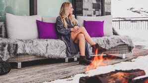 Une personne assise sur un canapé, devant un feu.