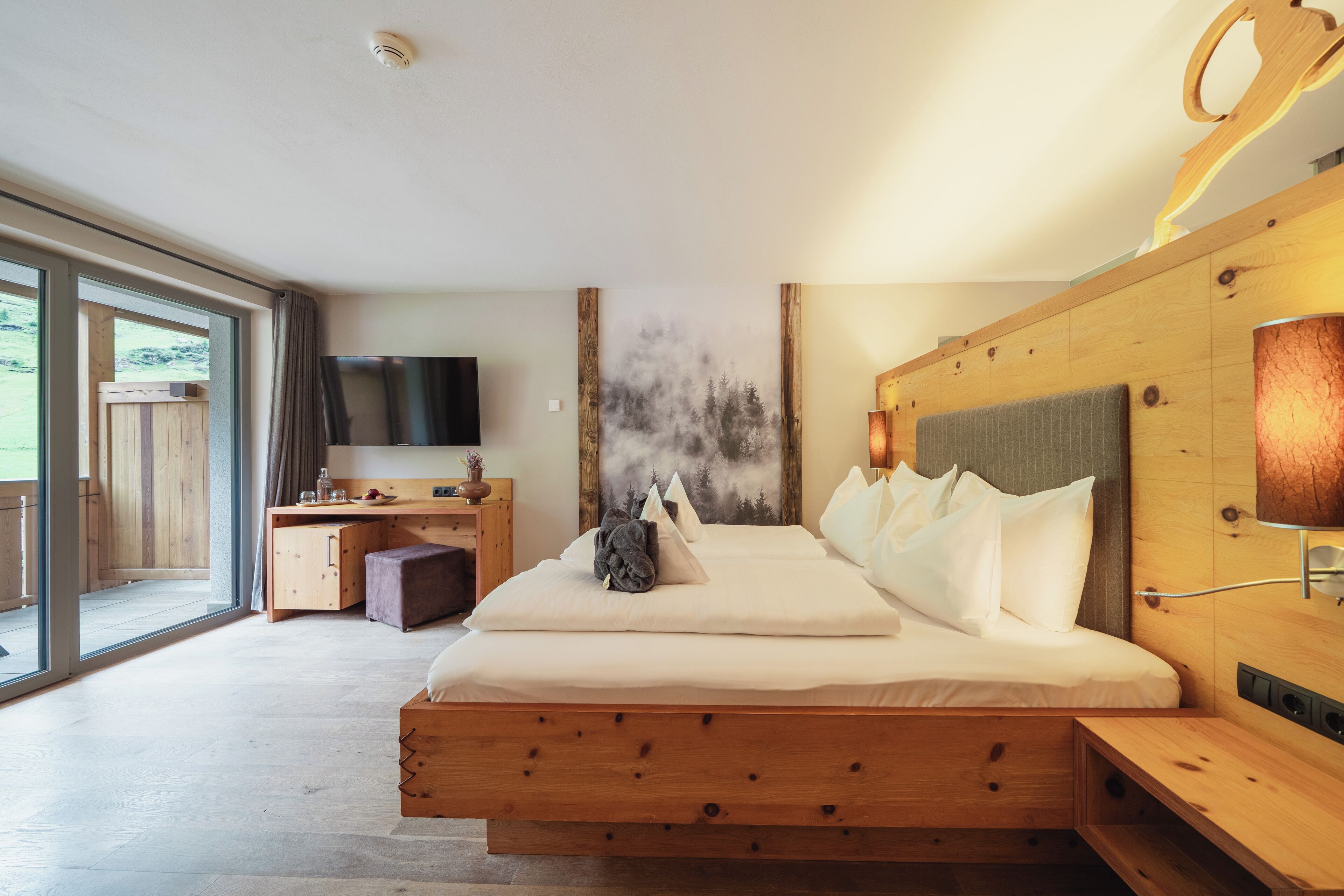 A modern bedroom with a wooden bed, a desk, and a television.