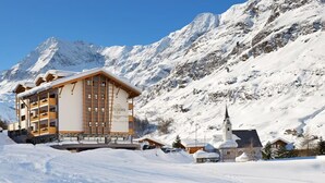 Un hôtel à la façade en bois, doté de nombreux balcons et situé au pied d’une montagne.