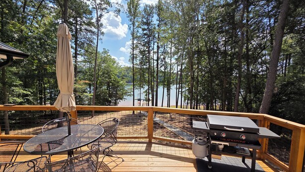 Eine Holzterrasse mit Grill und Gartenmöbeln.