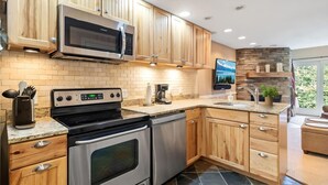 A modern kitchen with wooden cabinets, stainless steel appliances, and a stone backsplash.