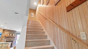 A staircase with carpeted steps leading to a wooden wall with a handrail.