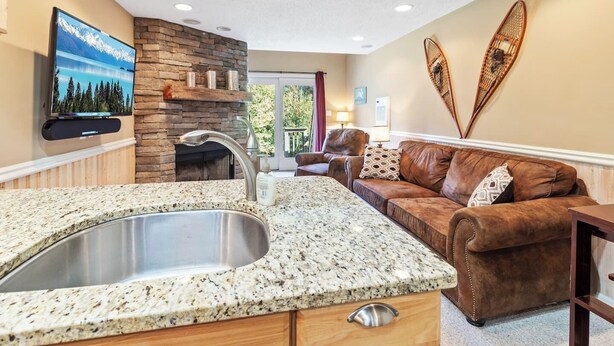 A modern kitchen with granite countertops, a stainless steel sink, and a stone backsplash.