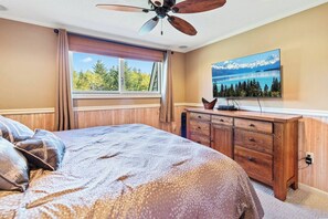Ein Schlafzimmer mit einem großen Bett, einem Holzschrank und einem Fernseher an der Wand.