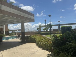 An outdoor area with a pool, seating, and a Ferris wheel in the background. - Levi & Moon's Chill with beautiful view (Pasay)