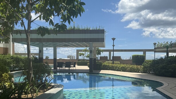 Une piscine dont le fond est décoré de motifs en mosaïque, entourée de verdure et dotée d’un espace détente abrité.