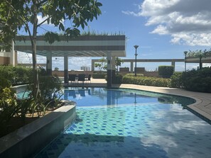 A swimming pool with tiled patterns, surrounded by greenery and a covered seating area. - Levi & Moon's Chill with beautiful view (Pasay)
