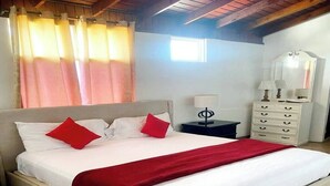 Una camera da letto con un letto, un comodino, una cassettiera e una finestra con tende.