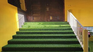 Una scala con gradini in erba sintetica che porta a una porta di legno.