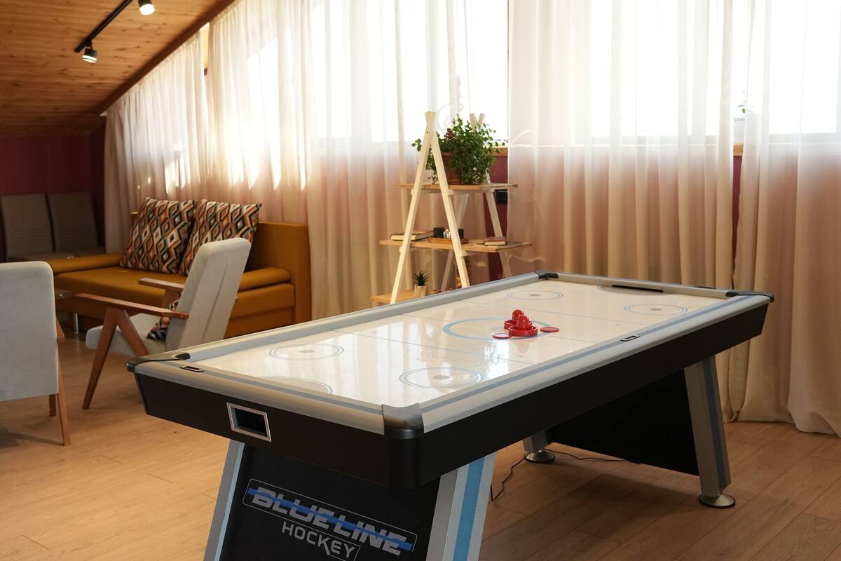A pool table in a room with wooden flooring and a sloped ceiling.