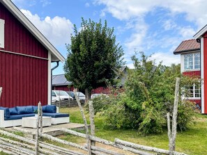 A red building with a white window, a tree, and a wooden fence.