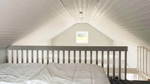 A bedroom with a sloped ceiling, a wooden headboard, and a framed picture on the wall. - 4 Person Holiday Home in Berga (Berga)