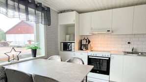 A modern kitchen with white cabinets, a built-in oven, a microwave, and a dining area with a table and chairs. - 4 Person Holiday Home in Berga (Berga)