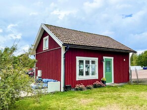 A red single-story building with a sloped roof, a green door, and white-framed windows.