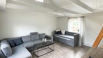 A modern living room with a grey sectional sofa, a small coffee table, and a grey sofa bed.