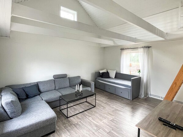 A modern living room with a grey sectional sofa, a small coffee table, and a grey sofa bed. - 4 Person Holiday Home in Berga (Berga)