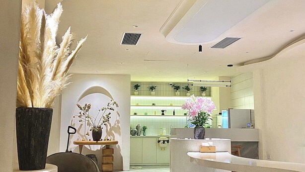 A modern interior with a curved ceiling, recessed lighting, and a kitchen area in the background. - J Village Hotel - Triệu Việt Vương (Hanoi)
