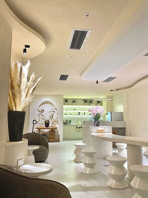 A modern interior with a curved ceiling, recessed lighting, and a kitchen area in the background. - J Village Hotel - Triệu Việt Vương (Hanoi)