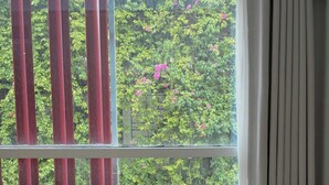 A room with a large window, a laptop on a glass table, two chairs, and a cup. - J Village Hotel - Triệu Việt Vương (Hanoi)