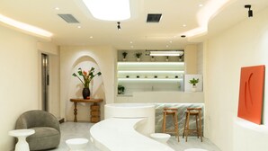 A modern reception area with a curved reception desk, multiple seating options, and a marble floor. - J Village Hotel - Triệu Việt Vương (Hanoi)