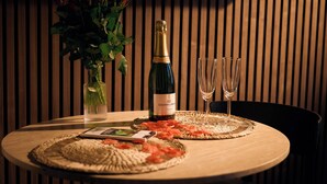 A round table with a bottle of wine, two glasses, a vase with flowers, and a menu. - Atypical suite with private jacuzzi - downtown Cognac (Cognac)