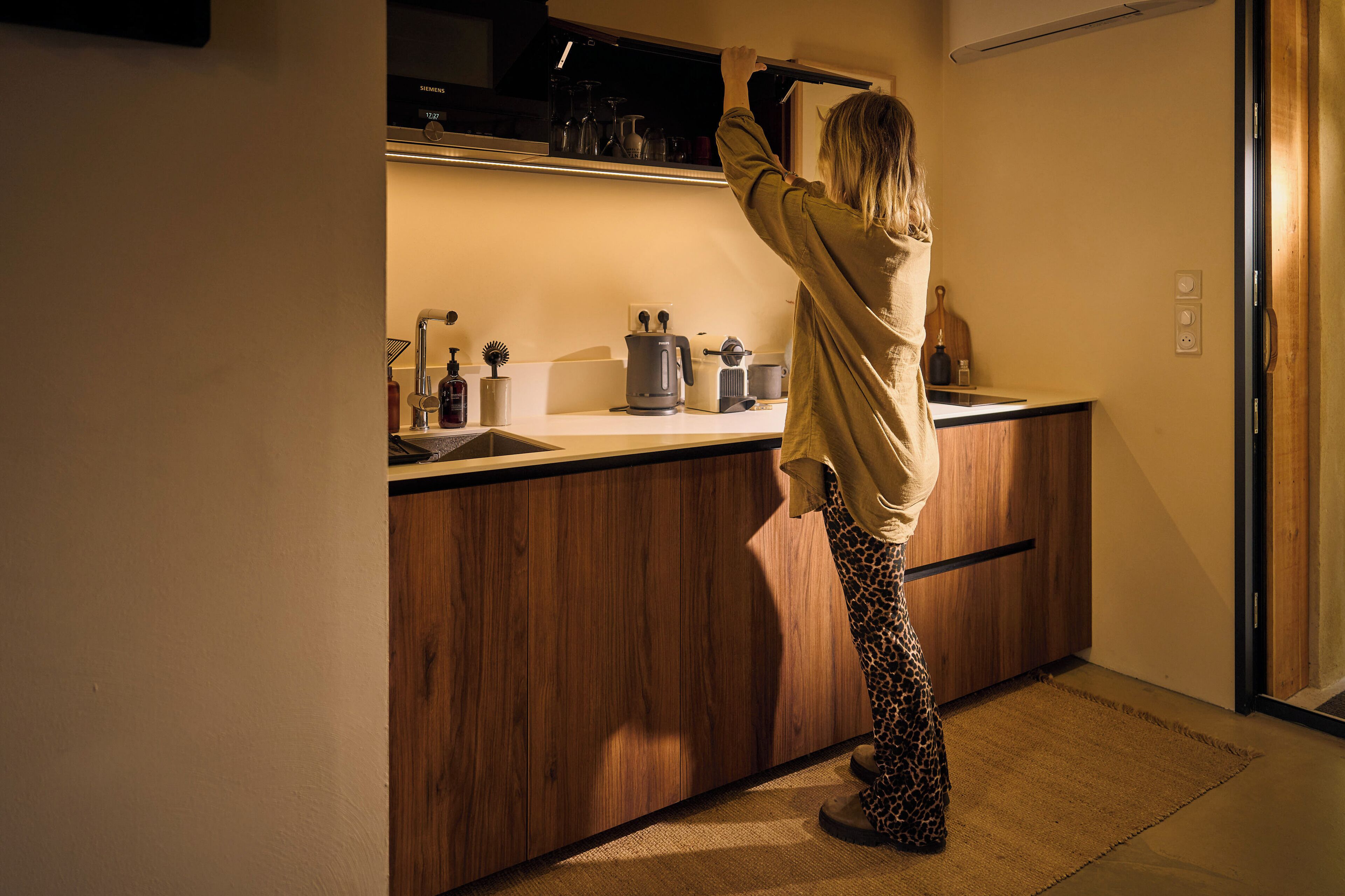 Una persona en una habitación con un armario de madera y una encimera.
