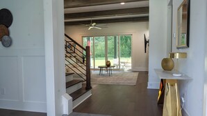 Un vaste espace de vie comprenant un escalier, un ventilateur de plafond et une vue sur l’extérieur.